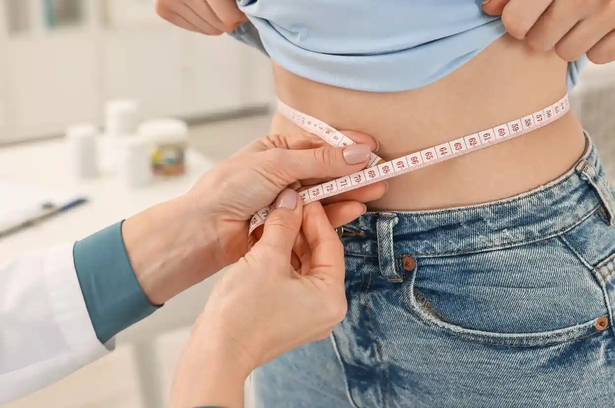 Woman Measuring her waist with tape after GLP-1 Weight Loss Treatment